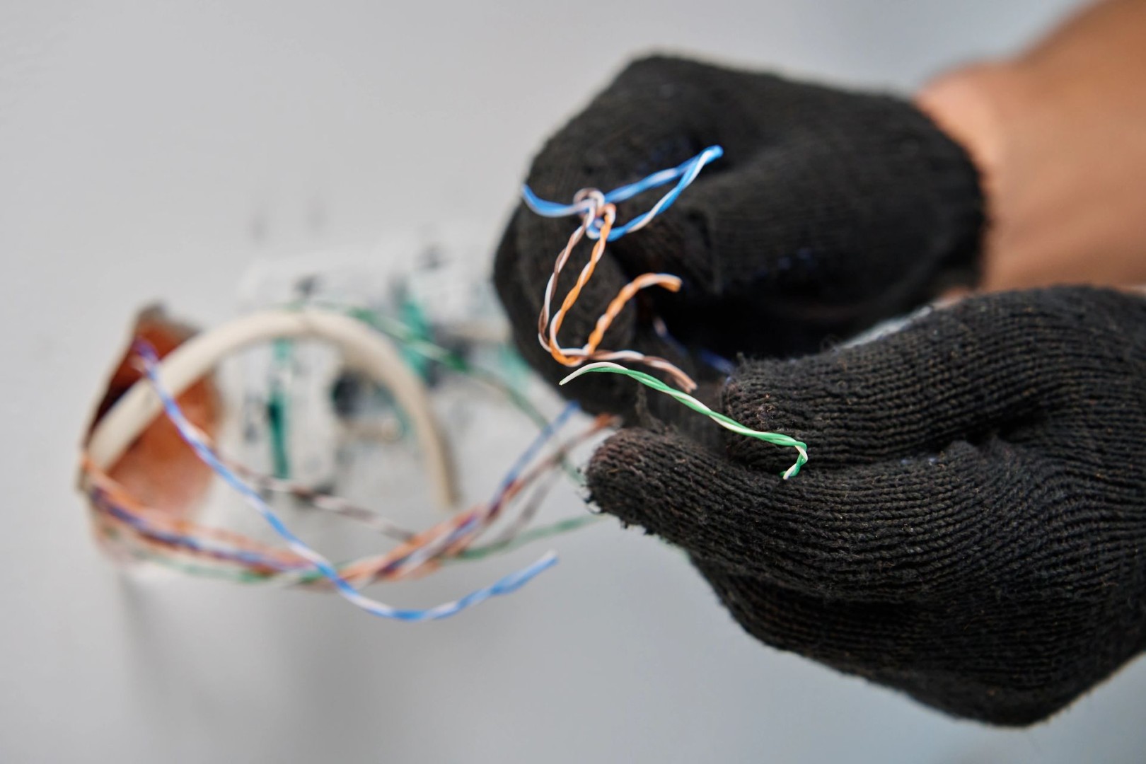 Technician terminating low-voltage structured wiring inside a multi-dwelling unit wall outlet.